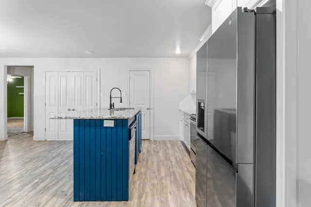 a kitchen with granite countertop a refrigerator a sink and wooden floors