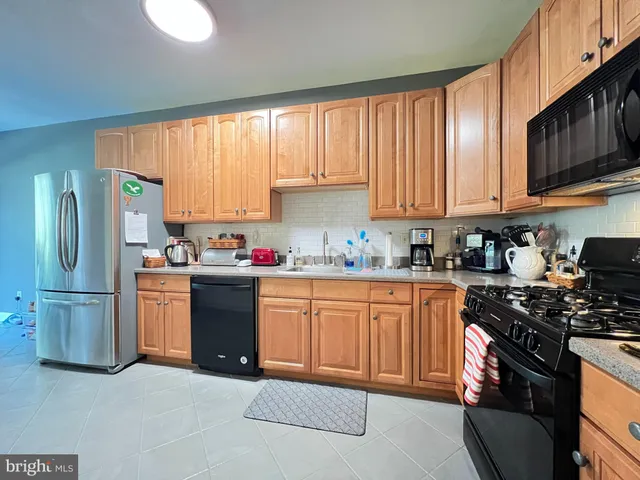 a kitchen with granite countertop stainless steel appliances a refrigerator stove top oven and sink