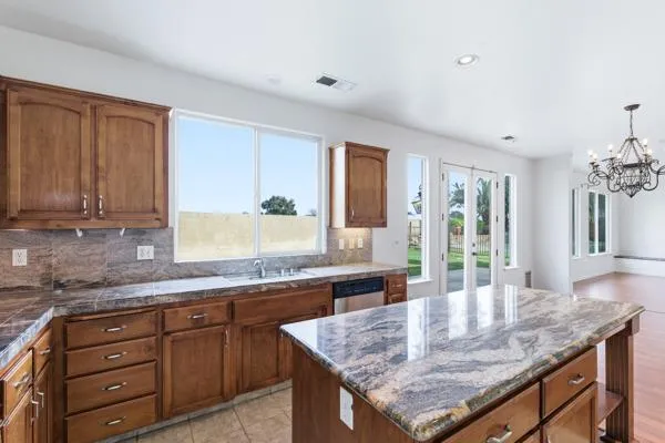 a kitchen with granite countertop kitchen island stainless steel appliances a sink stove and cabinets