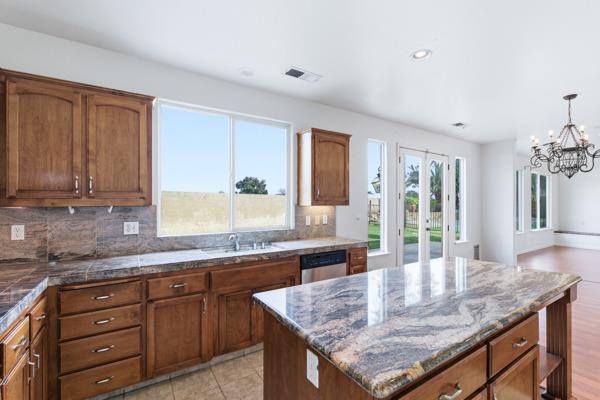 384 Millbrook Street Hanford, CA 93230 - Photo 11 of 59 a kitchen with granite countertop kitchen island stainless steel appliances a sink stove and cabinets