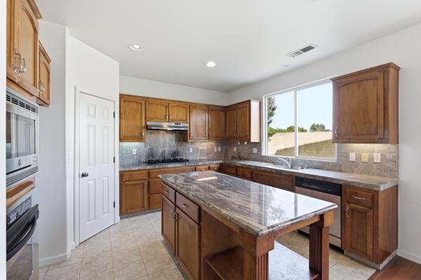 384 Millbrook Street Hanford, CA 93230 - Photo 22 of 59 a kitchen with a stove a sink and a refrigerator