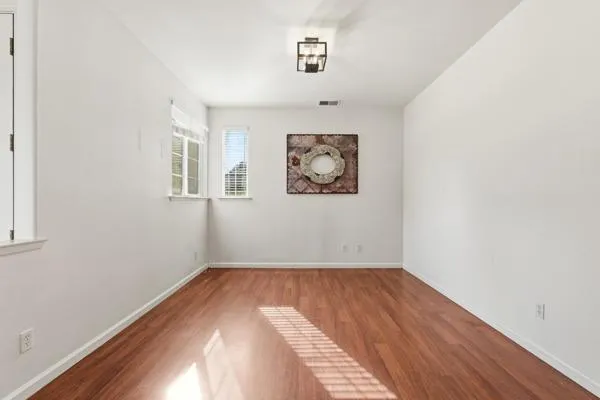 an empty room with chandelier fan and windows