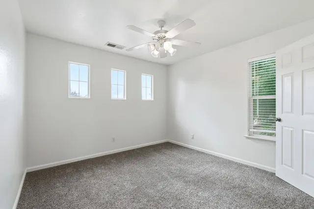 an empty room with a chandelier fan and closet