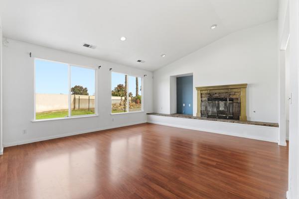 384 Millbrook Street Hanford, CA 93230 - Photo 8 of 59 a view of an empty room with a window and wooden floor