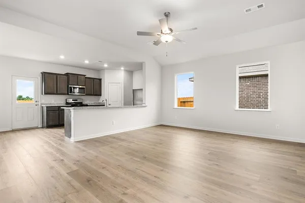 a view of kitchen with microwave a stove a sink dishwasher and a refrigerator with wooden floor