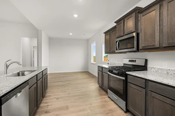 a kitchen with stainless steel appliances granite countertop a sink stove microwave and cabinets
