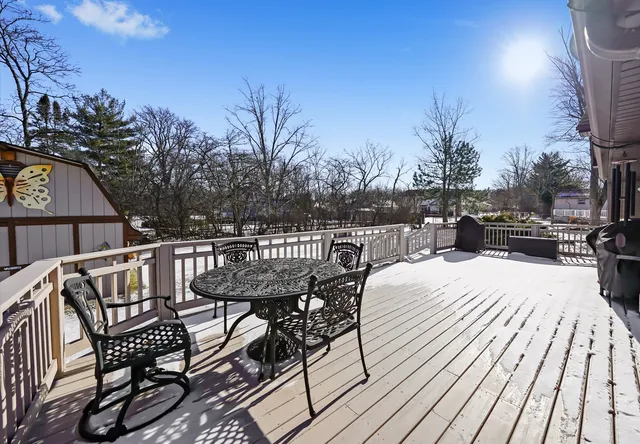 a view of a roof deck with table and chairs with wooden floor and fence