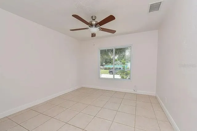 an empty room with windows and ceiling fan