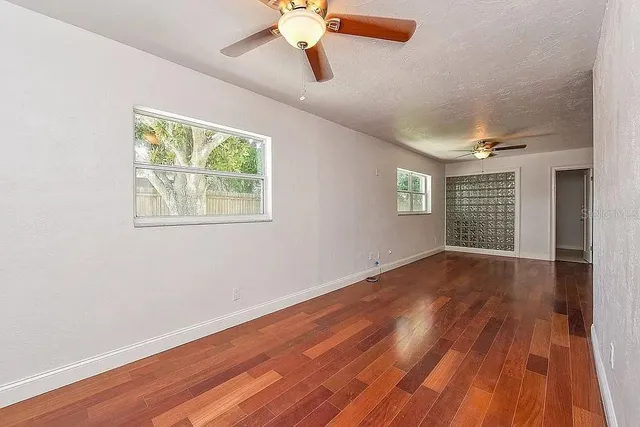 a view of an empty room with wooden floor and a window