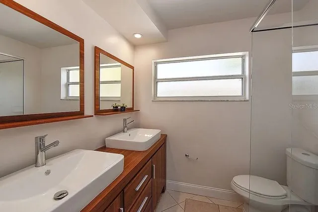 a bathroom with a toilet a sink a mirror and a window