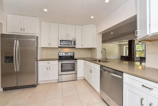 a kitchen with granite countertop a refrigerator sink and cabinets