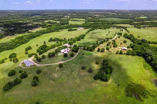 an aerial view of a residential houses with outdoor space and trees