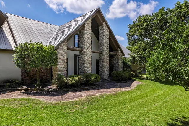 a view of a house with brick walls and a yard with plants