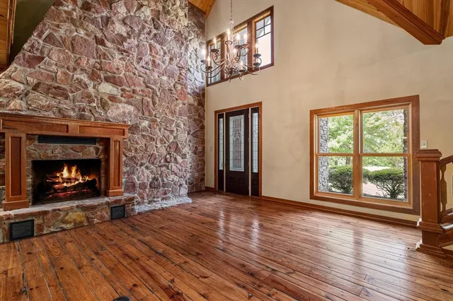a view of an empty room with wooden floor fireplace and a window