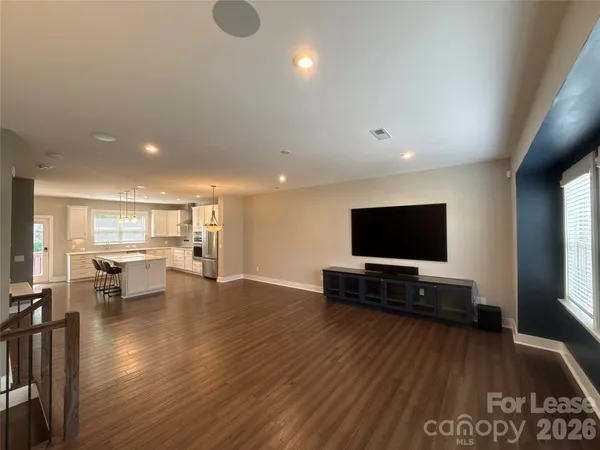 a view of an empty room with wooden floor and stairs