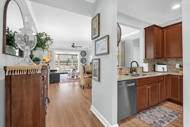 a kitchen with stainless steel appliances granite countertop a refrigerator a sink dishwasher and wooden cabinets with wooden floor