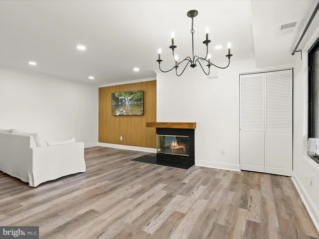 a view of a livingroom with a fireplace a chandelier and wooden floor