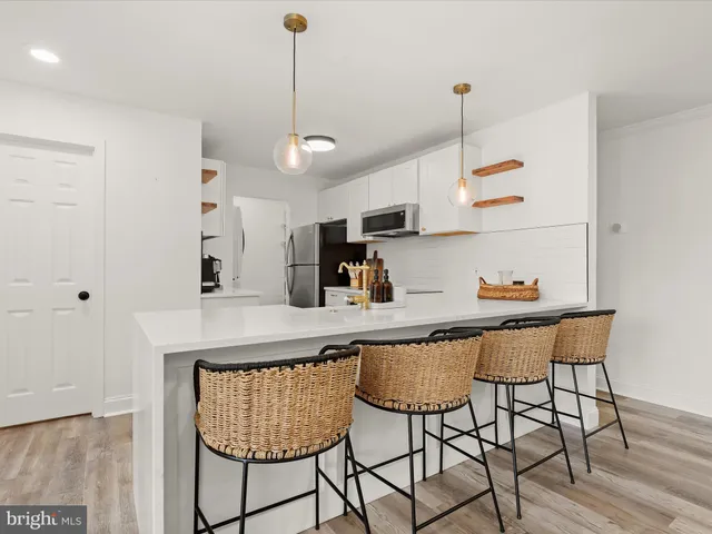 a kitchen with stainless steel appliances granite countertop a dining table chairs refrigerator and sink