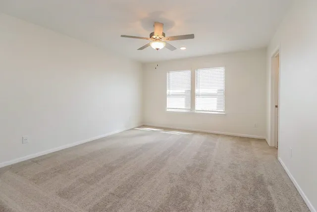 an empty room with window and ceiling fan