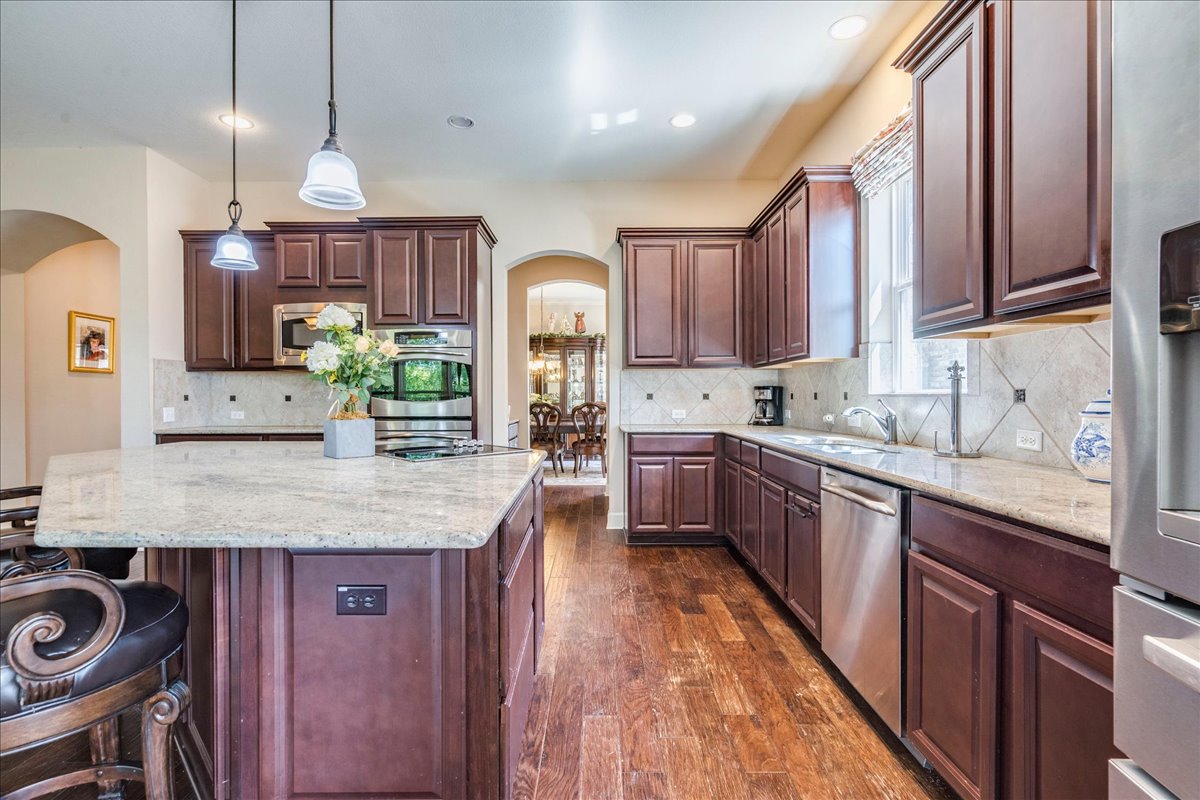 12909 Medina River Way Austin, TX 78732 - Photo 13 of 36 Rich wood cabinetry and expansive granite countertops define this well-appointed kitchen space.