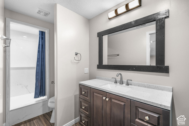1045 West 3600th South Perry, UT 84302 - Photo 34 of 57 Bathroom featuring a vanity with a white countertop, wood-finish flooring, a dark wood-framed mirror, and a shower with white surround