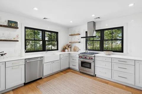 a kitchen with white cabinets window and stainless steel appliances
