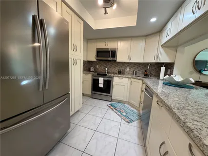 a kitchen with granite countertop a sink a stove a microwave and cabinets