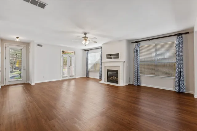 an empty room with wooden floor fireplace and windows
