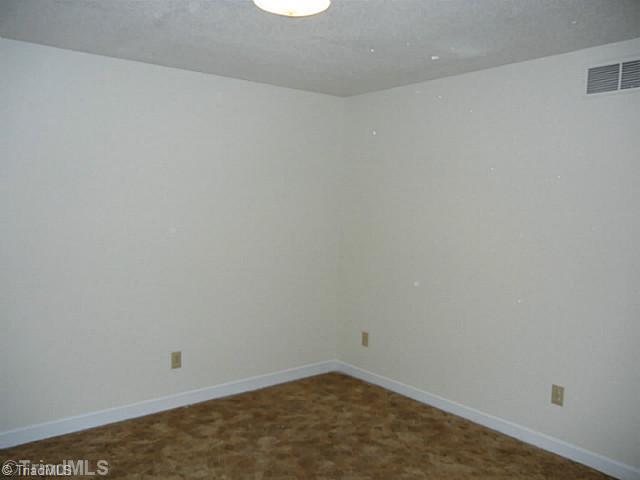 1411 Chesterfield Road Lewisville, NC 27023 - Photo 12 of 16 3rd Bedroom. Lower level bedroom with neutral decor and an overhead light fixture. There is a full bath on this level as well and is off the walk out playroom.