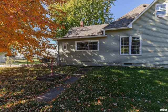 a front view of house with yard and trees in the background