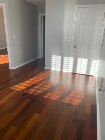 a view of an empty room with window and wooden floor