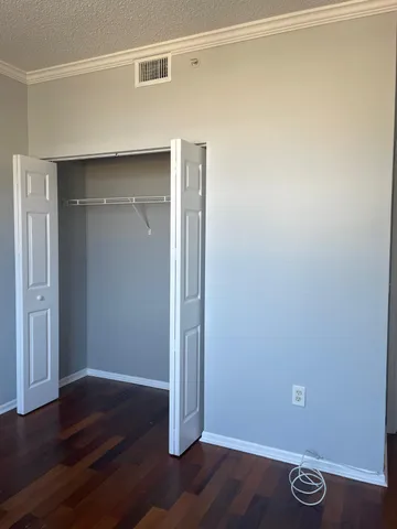a view of an empty room with wooden floor and closet