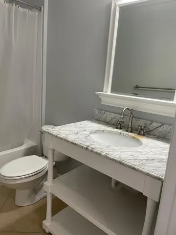 a bathroom with a granite countertop sink toilet and mirror