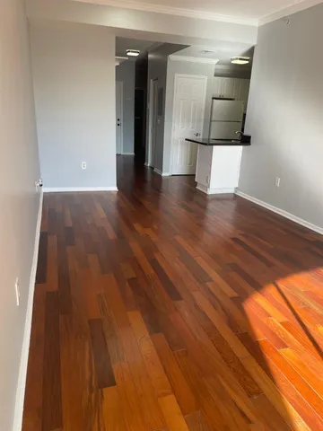 a view of a hallway with wooden floor and cabinets