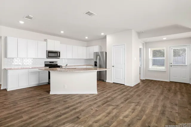 a kitchen with granite countertop white cabinets and stainless steel appliances