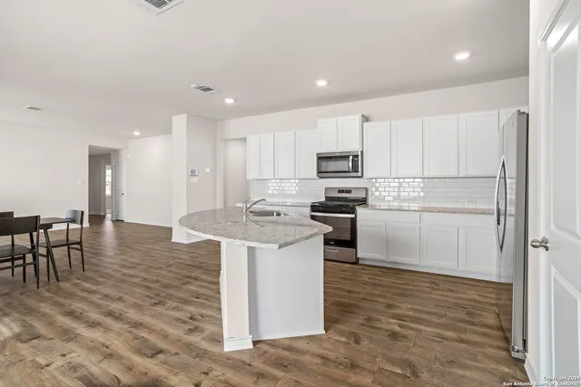 a kitchen with kitchen island a sink a stove a refrigerator and white cabinets