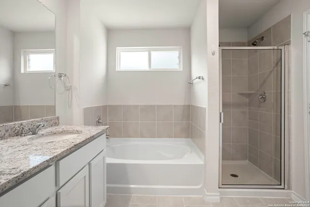a bathroom with a granite countertop sink a mirror bathtub and shower