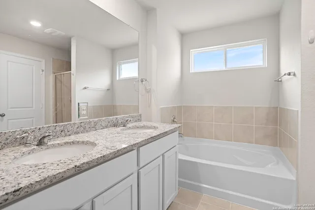 a bathroom with a granite countertop sink and a bathtub