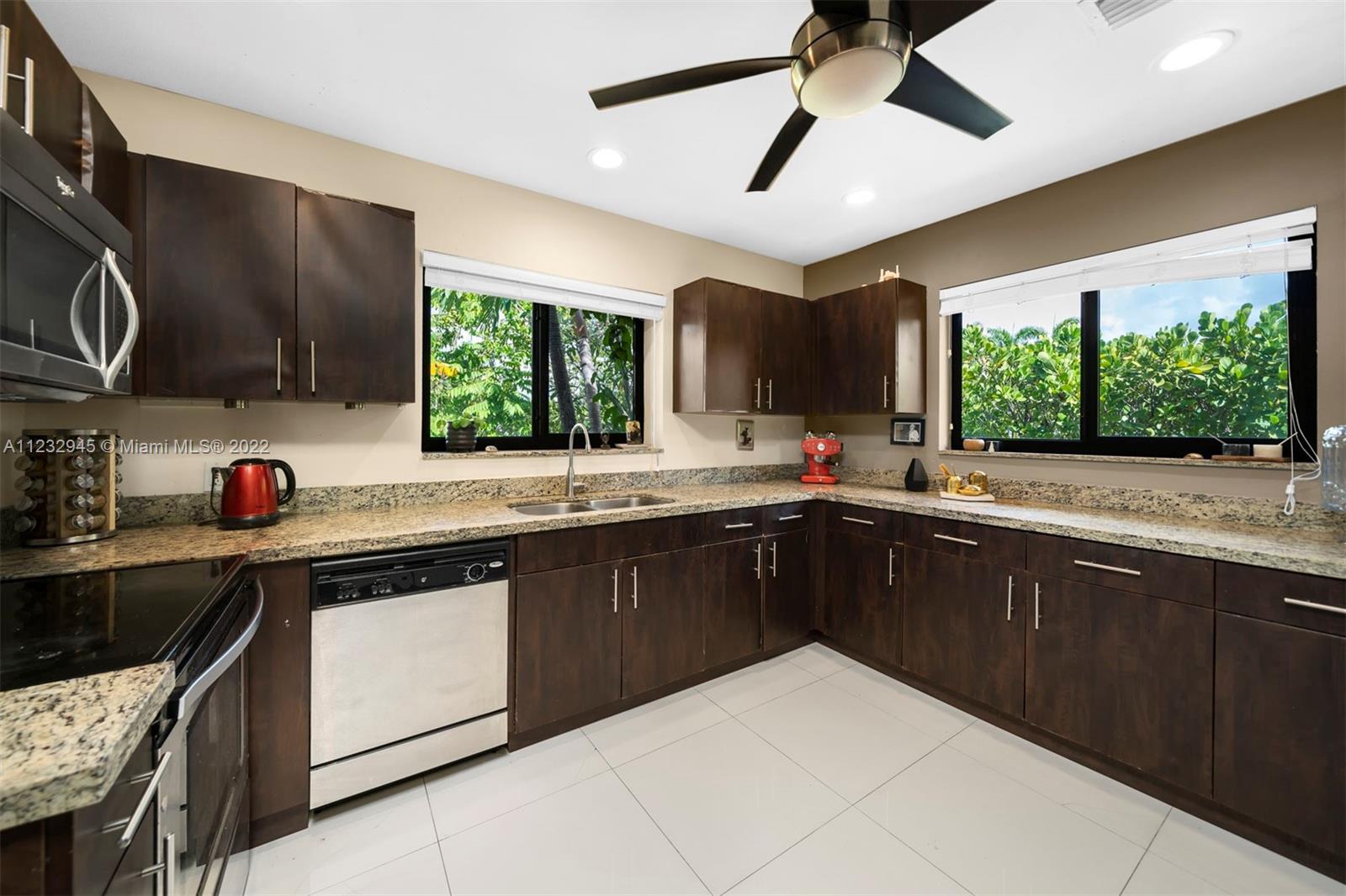 1598 Normandy Drive Miami Beach, FL 33141 - Photo 4 of 40 a kitchen with stainless steel appliances granite countertop a sink and dishwasher a stove top oven with wooden floor