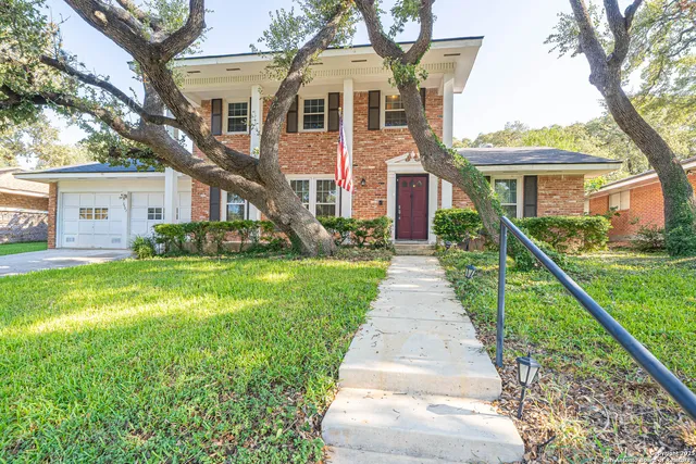 a front view of a house with a yard and potted plants