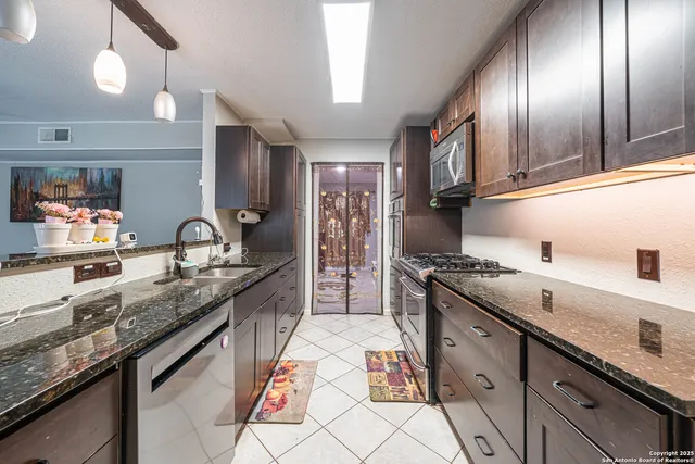 a kitchen with granite countertop stainless steel appliances a sink stove top oven and cabinets