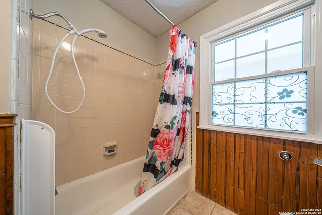 a bathroom with a bathtub a shower and a window