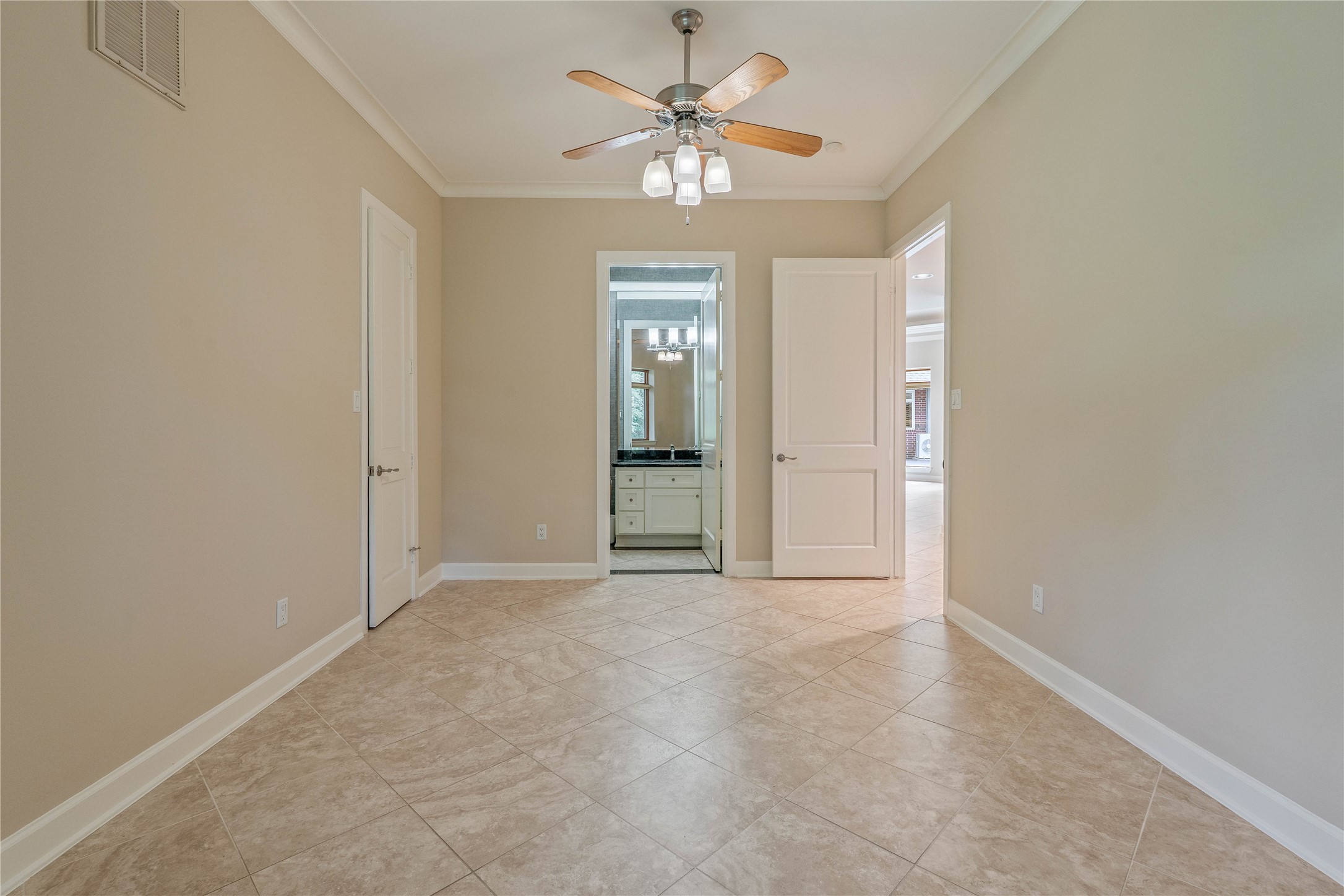 16621 Hereford Road Tomball, TX 77377 - Photo 28 of 46 This bedroom features elegant tile flooring, soothing neutral walls, and a stylish ceiling fan, seamlessly connecting to a chic ensuite bathroom for ultimate comfort and convenience.