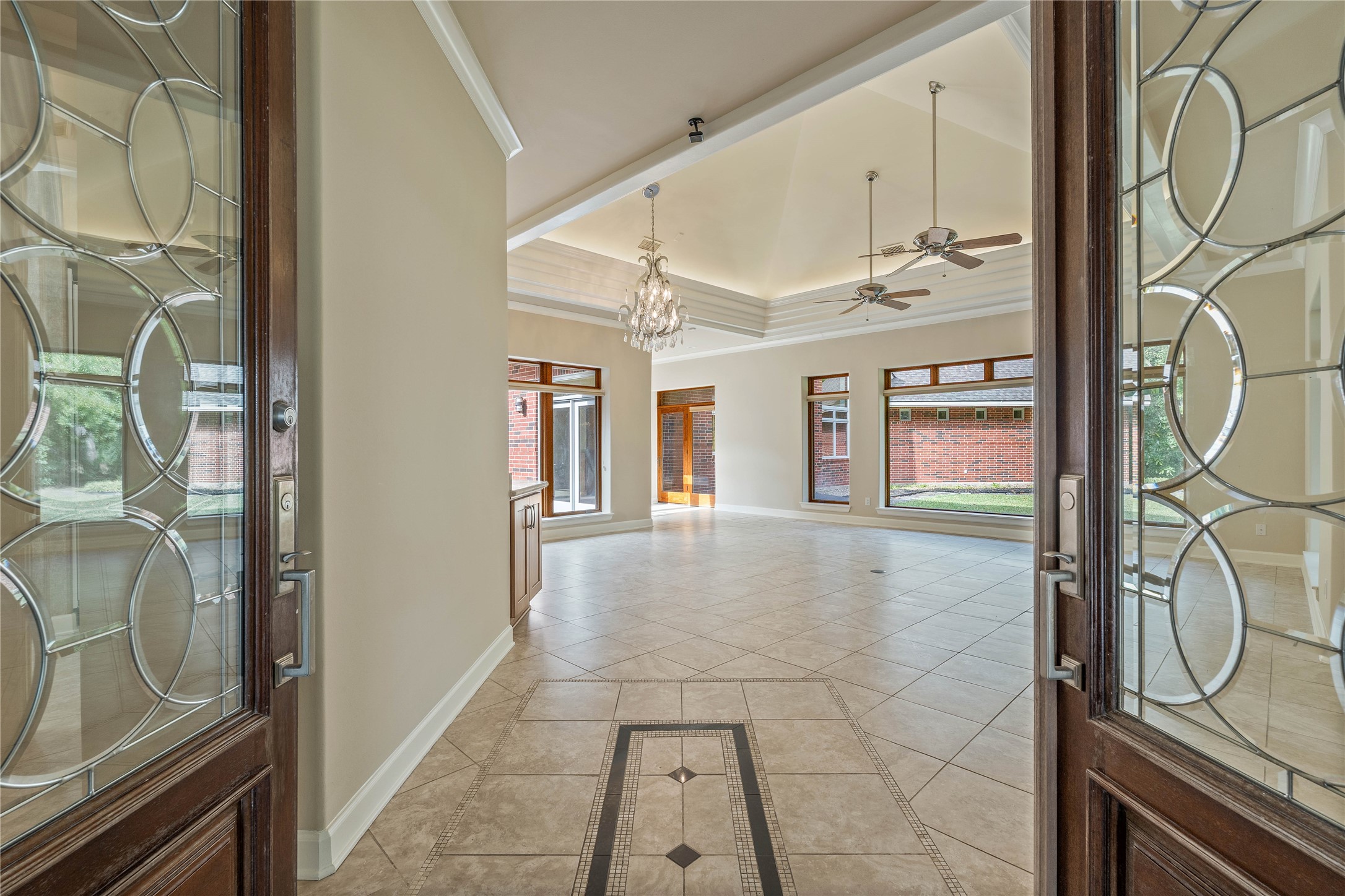 16621 Hereford Road Tomball, TX 77377 - Photo 6 of 46 This spacious entryway features elegant double doors with decorative glass, leading into a bright, open living area with high ceilings, modern chandeliers, and large windows that offer abundant natural light. The tiled floor enhances the room's contemporary feel.