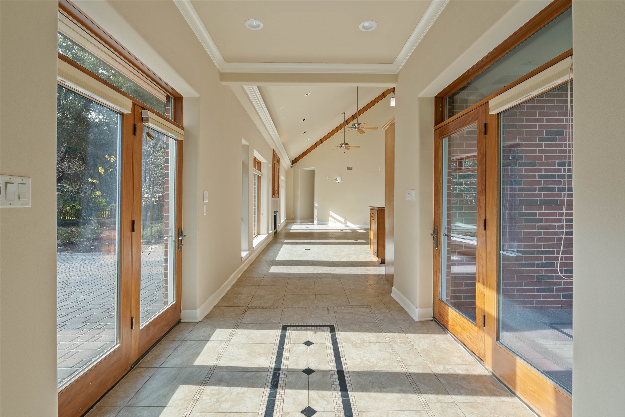 16621 Hereford Road Tomball, TX 77377 - Photo 8 of 46 This bright hallway features large glass doors on both sides, allowing natural light to flood in. The space is accented with cream-colored walls and elegant tile flooring, creating a welcoming and airy atmosphere.