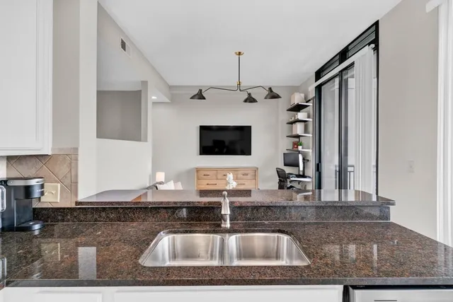 a kitchen with kitchen island granite countertop a sink a counter top space cabinets and stainless steel appliances