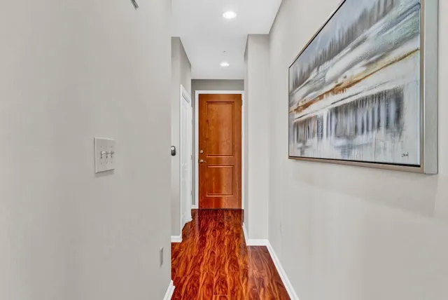 a view of a hallway with wooden floor and a bathroom