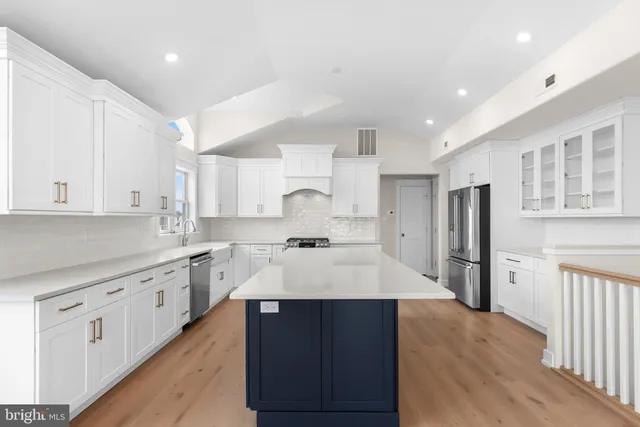 a large white kitchen with wooden floor and cabinets
