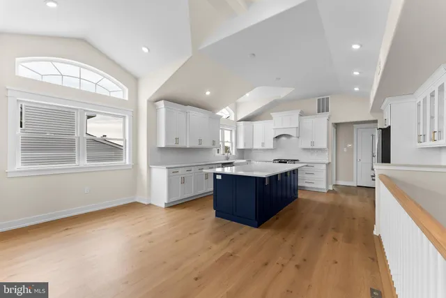 a large kitchen with stainless steel appliances kitchen island a large counter top and wooden floors