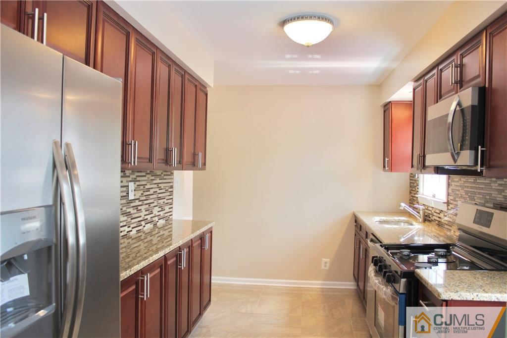 15 Roberts Road New Brunswick, NJ 08901 - Photo 9 of 25 a kitchen with stainless steel appliances granite countertop a refrigerator a stove and a sink with wooden floor
